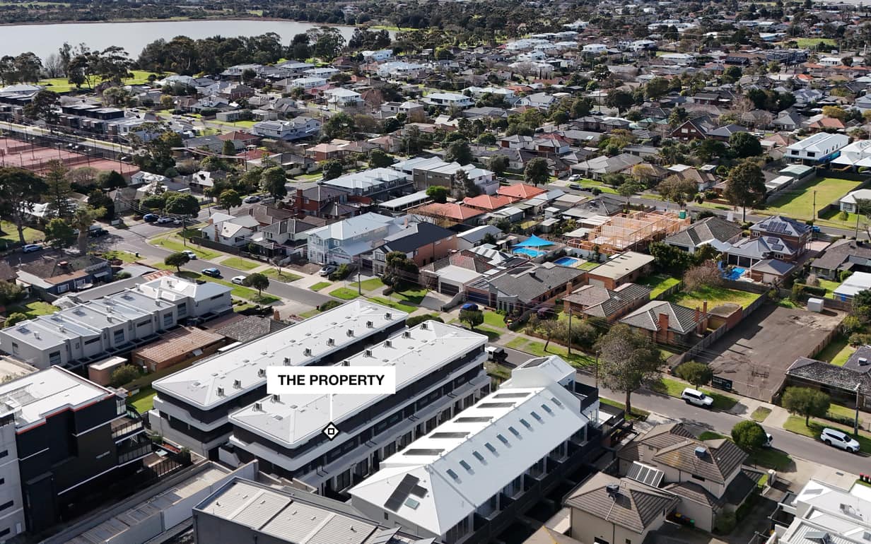 A real pinned photo from the Pin the Lot engine: our own drone photo of a bayside Melbourne street with the property marked by a plate reading THE PROPERTY, no place pins on this single frame, the neighbourhood and the lake behind it.